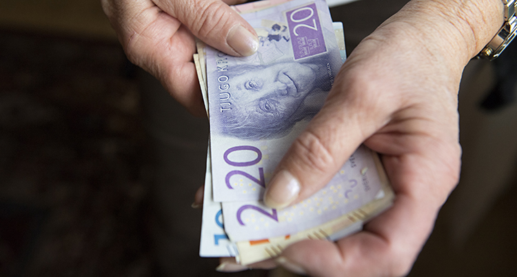 Två rynkiga händer håller i en bunt med sedlar