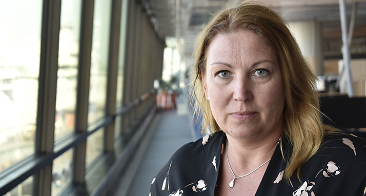 Kvinnan har brunt hår och svart skjorta