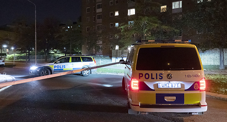 Två polisbilar och en avspärrning framför ett hus. Det är mörkt ute.