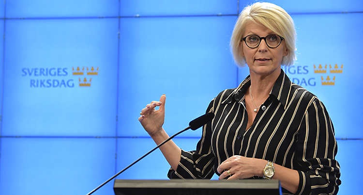 Hon har blont hår och glasögon, randig skjorta