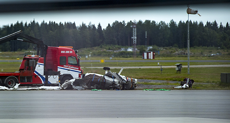 En lastbil bakom svarta och vita vridna flygplansdelar.