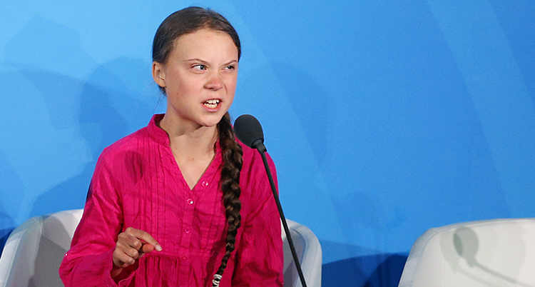 Greta har en rosa skjorta och ser arg ut i ansiktet, hon pekar med ena handen