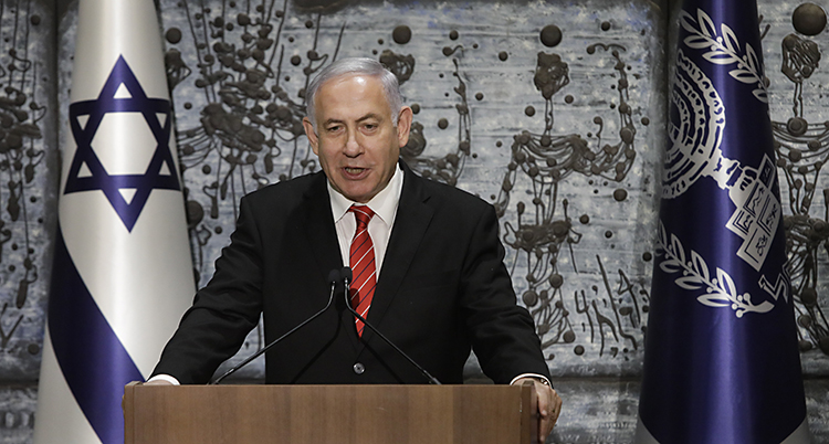 Benjamin Netanyahu står framför Israels flagga som är vit med en blå stjärna