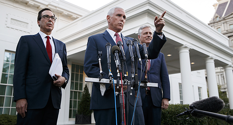 Mike Pence i kostym ser allvarlig ut och pekar med handen i luften. Han står framför flera mikrofoner. Bakom honom två allvarliga män.