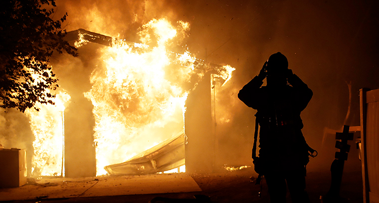 En brandman står framför en stor eld. Han försöker släcka den.
