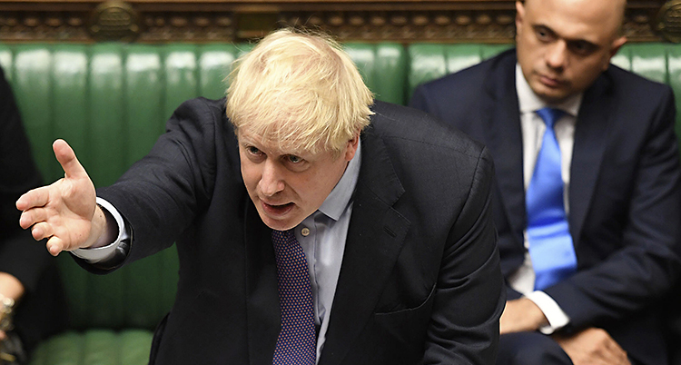 Johnson lutar sig fram i en talarstol och pratar.