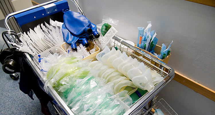 En vagn på ett sjukhus med en mängd olika saker som behövs till en operation. Bland annat slangar och masker av plast.