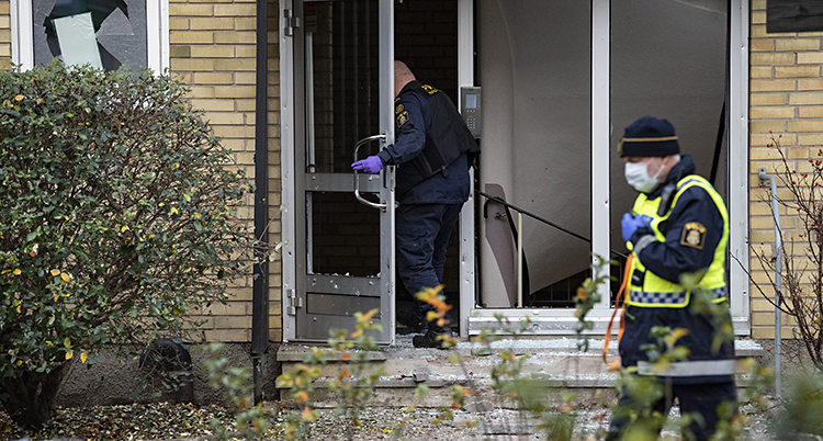 Två poliser vid huset. Alla fönster i dörrarna är trasiga.
