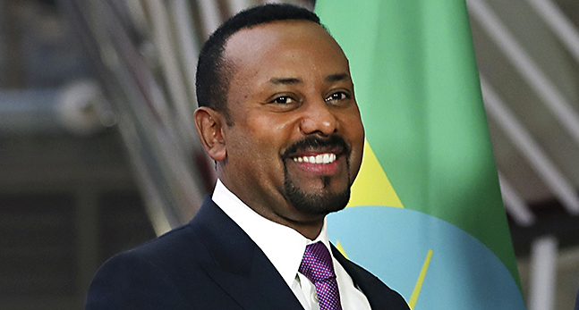Abiy Ahmed i mörk kostym och lila slips ler mot kameran.