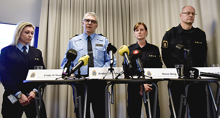 En bild från en presskonferens. Fyra chefer i polisen står vid ett bord och pratar. Det är två kvinnor och två män. På bordet finns flera mikrofoner från journalisterna.