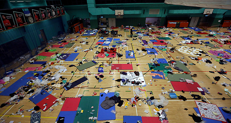 En gymnastiksal som är fotograferad uppifrån. På golvet syns massor av madrasser och andra saker.