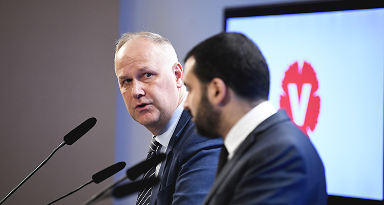 Vänsterpartiets ledare Jonas Sjöstedt och Ali Esbati. De har mikrofoner framför sig. I bakgrunden syns Vänsterpartiets logga.