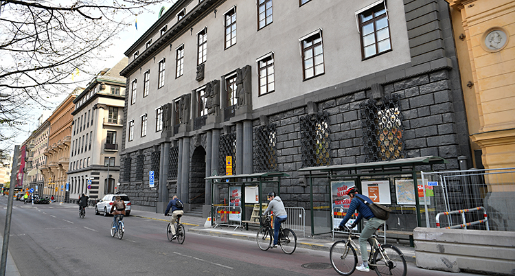 En bild på SEBs stota hus av sten. Några människor cyklar förbi.