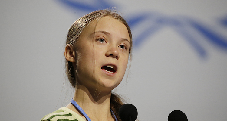 Greta Thunberg talar. Hon har en mikrofon framför sig.