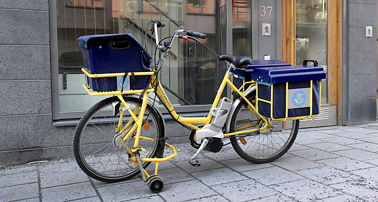 En cykel från Postnord står parkerad på en trottoar.