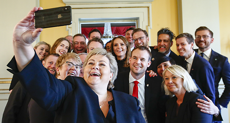 Erna håller upp en mobil och tar bild på hela den glada gruppen