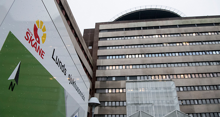 Bilden visar ett stort grått hus. Framför huset finns en skylt där det står Lunds sjukhusområde.