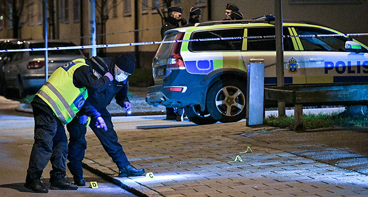 En avspärrning utomhus. Poliser söker ledtrådar på marken.