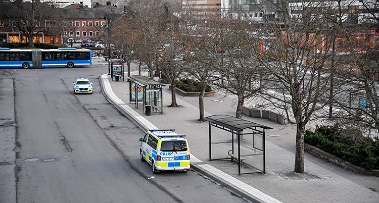 Ett torg för bussar i Sollentuna. Bilden är tagen uppifrån, ner på torget. Nere på torget syns två polisbilar och en blå buss och några träd.
