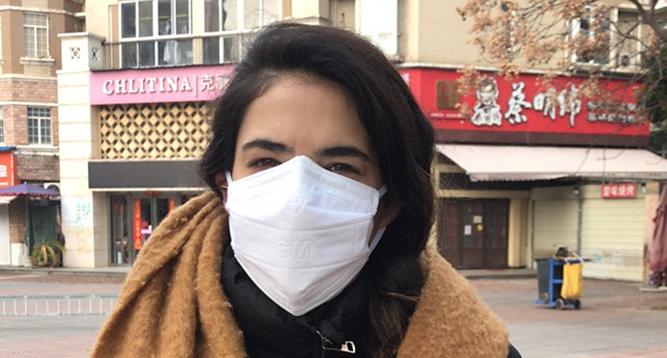 Angelica Kristiansson Herrera har munskydd på sig. Hon står ute i staden Wuhan där hon studerade. Nu har hon fått hjälp att åka hem till Sverige.
