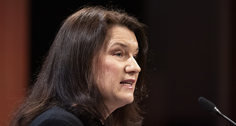 Ann Linde har mörkt hår. Hon talar framför en mikrofon.