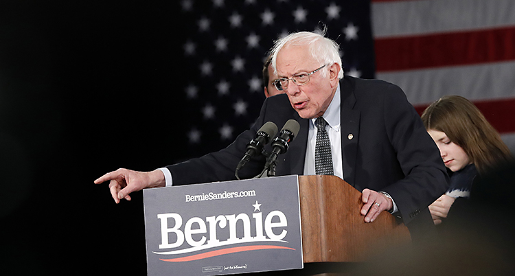 Bernie Sanders pratar. Han har två mikrofoner framför sig.