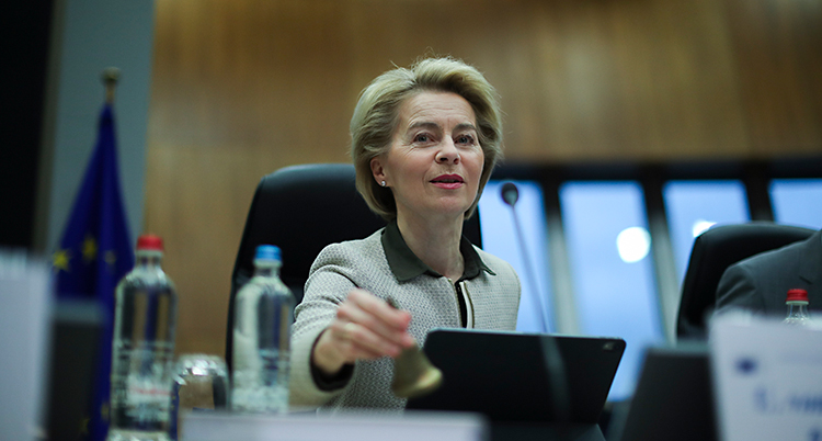 EUs ledare Ursula von der Leyen sitter vid ett bord och ringer i en iiten klocka. Det ska vara ett möte i EU.