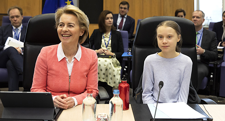 De sitter bredvid varandra vid ett skrivbord. EUs ledare ler stort. Greta ser mer allvarlig ut.