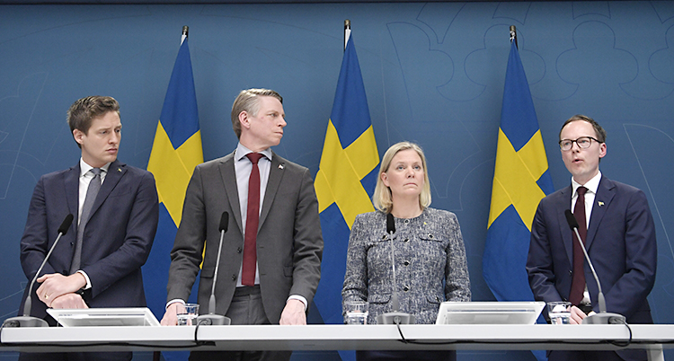 Tre män och en kvinna på rad framför svenska flaggor
