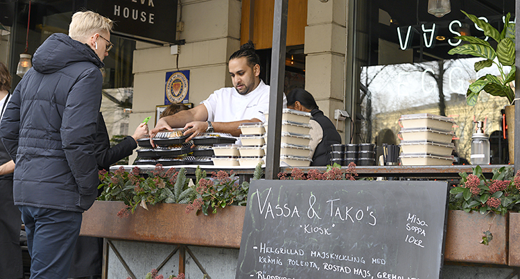 En servitör staplar upp lådor med mat utanför en restaurang