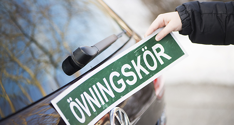 En skylt där det står Övningskör sätts fast på en bil