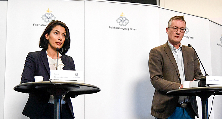 Bilden visar två personer som står på en scen. Till vänster står en kvinna vid ett ståbord med en mikrofon. Till höger står en man vid ett småbord med en mikrofon.