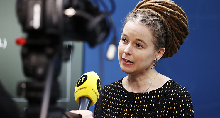 Kvinnan talar med en reporter som har en gul mikrofon i handen.