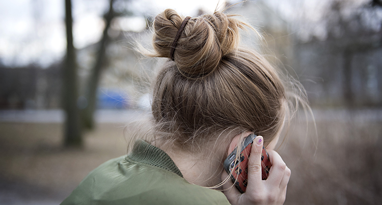 En flicka sitter med sin mobiltelefon vid örat.