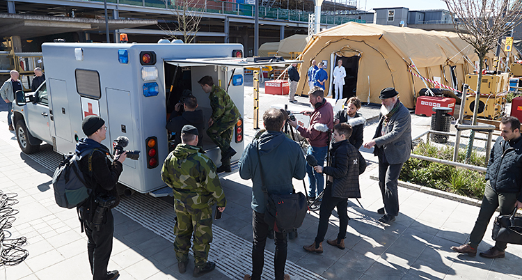 Folk samlade vid en ambulans. I bakgrunden ett stort brunt tält.
