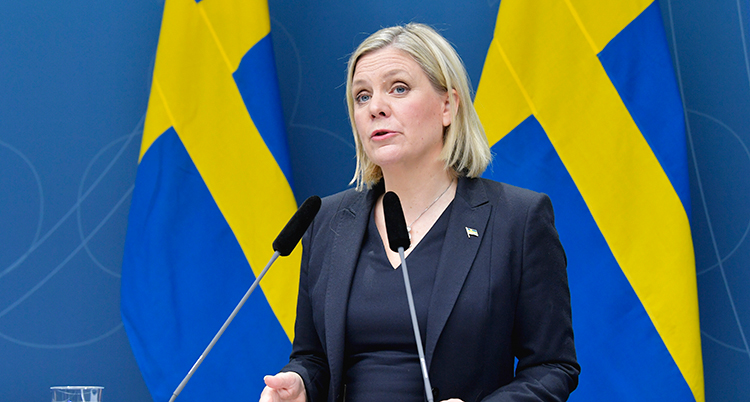 Magdalena Andersson talar. Bakom henne är två svenska flaggor