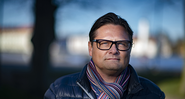 Han har glasögon och halsduk på sig.