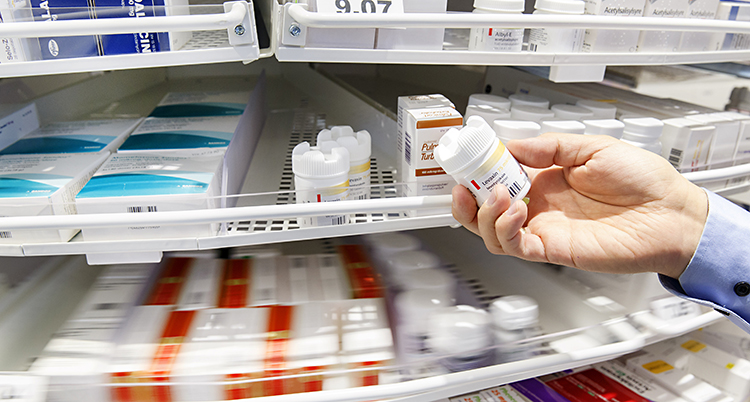 En hylla i ett apotek. Massor av burkar med medicin finns i hyllan.