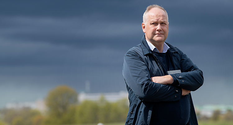 Jonas Sjöstedt står utomhus med armarna i kors. I bakgrunden är det mörka moln på himlen.