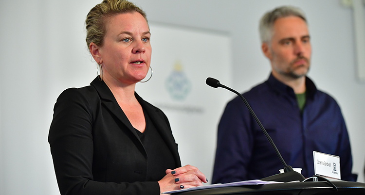 Johanna Sandwall i förgrunden framför en mikrofon. Anders Wallensten från Folkhälsomyndigheten i bakgrunden.