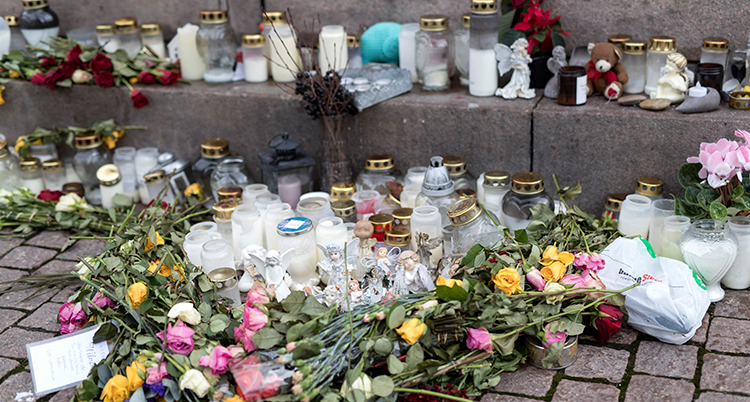 Blommor och ljus står på gatan.