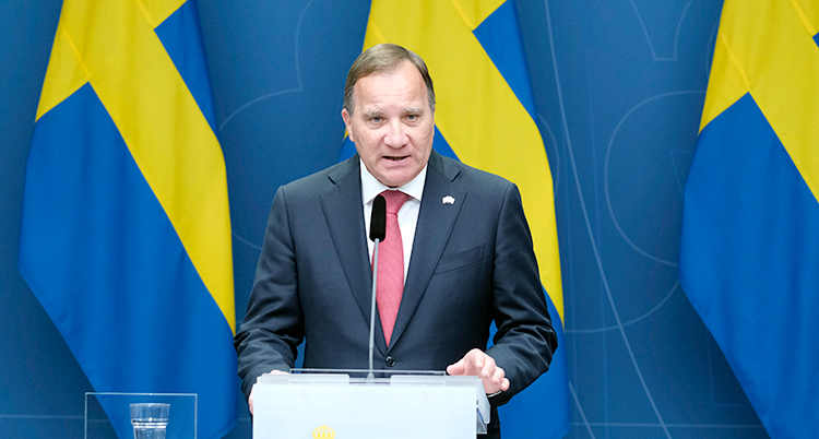 Löfven står vid en talarstol. Bakom honom finns svenska flaggor.