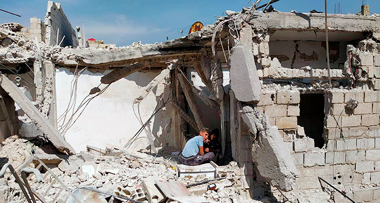 Små pojkar sitter i ruinerna av ett hus som har blivit förstört i kriget i Syrien.