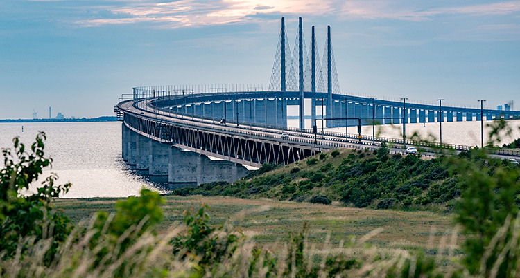 Bilden är tagen från land, ut mot havet. I havet syns en stor bro.