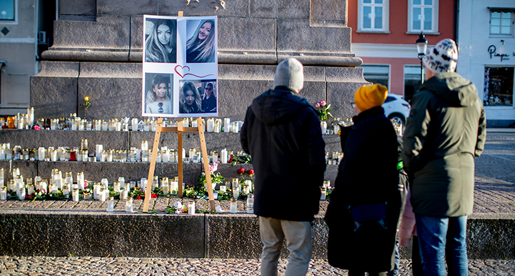människor står och tittar på tända ljus och bilder på wilma vid ett torg i Uddevalla.