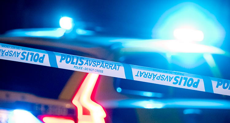 Bilden visar en polisavspärrning och blåljus från en polisbil.