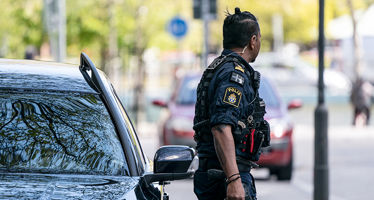 En polis står bredvid en bil.