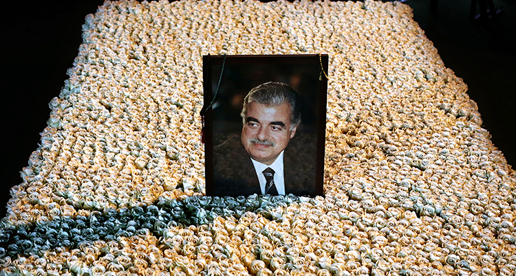 En bild av Libanons förre premiärminister Rafiq al-Hariri. Det är en bild på honom som står på hans grav. Graven är också täckt av blommor.