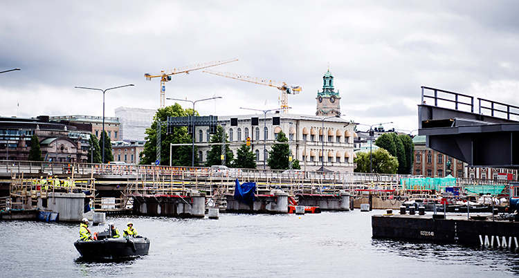 Bilden är tagen mitt i Stockholm. Det är en bro som går över vatten. Där är det folk som jobbar.