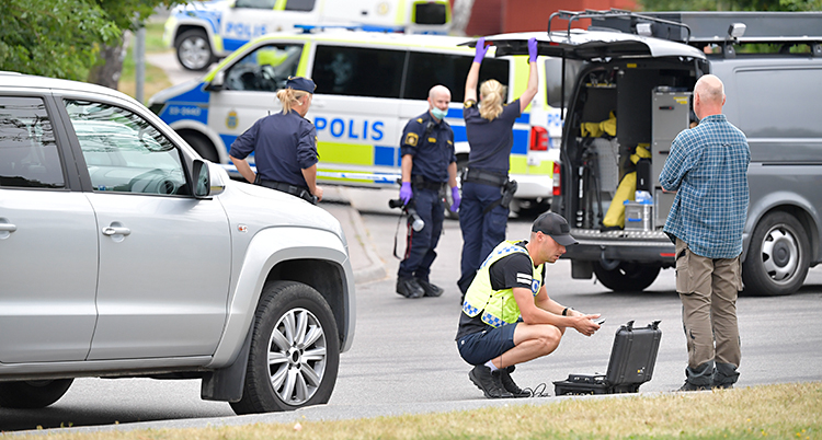 Bilden är tagen utomhus. Vi ser flera bilar och flera poliser.